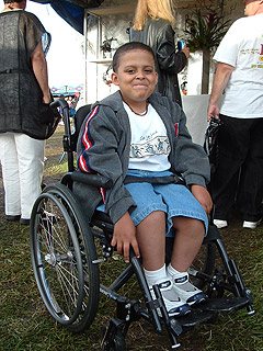 Photo: Smiling boy in wheelchair enjoying the crafts area at a festival.